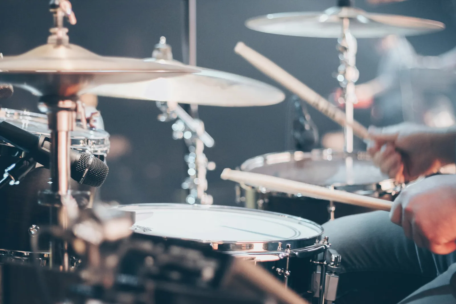 Drummer mid-stroke with sticks over a snare