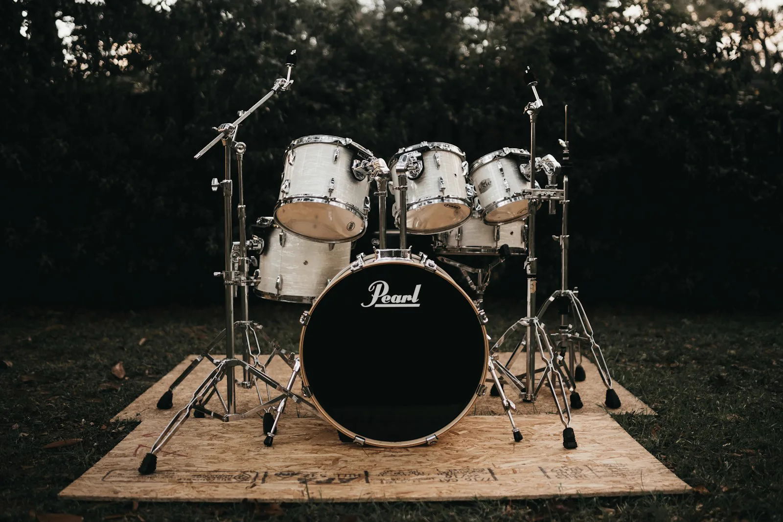 White drum kit set up outdoors on plywood